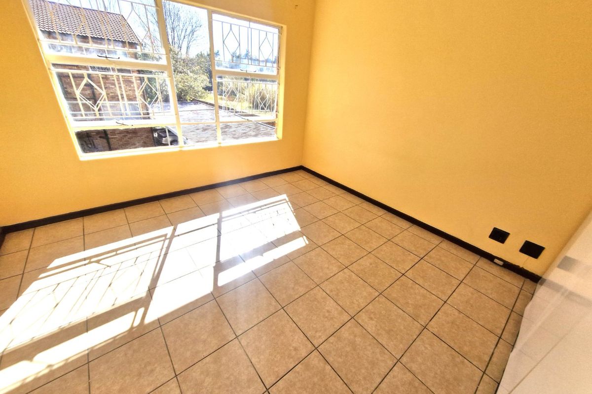 A bright, empty bedroom featuring tiled flooring and large windows fitted with security bars, offering a blank canvas for personalization.