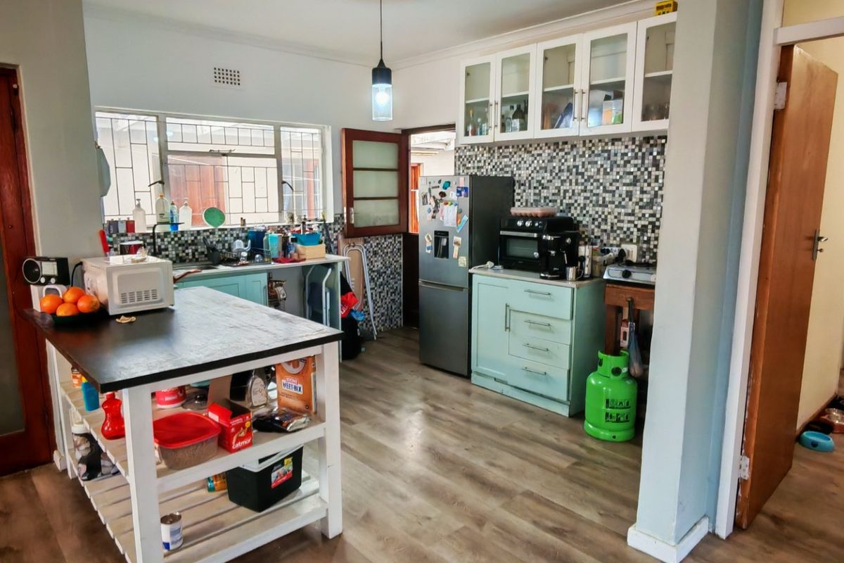 A functional kitchen featuring mosaic tile backsplashes, ample cabinetry, and laminate flooring, offering a practical layout with potential for modern cosmetic updates.
