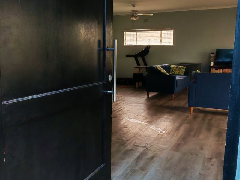 View from the front entrance into the living area, featuring wood-look laminate flooring and a ceiling fan.