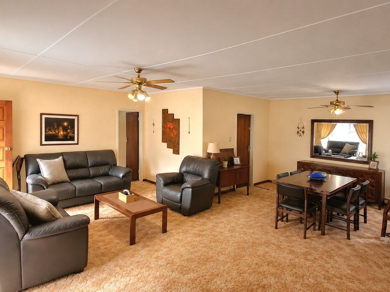 Spacious open-plan living and dining area featuring dual ceiling fans, neutral wall finishes, and traditional solid wood doors.