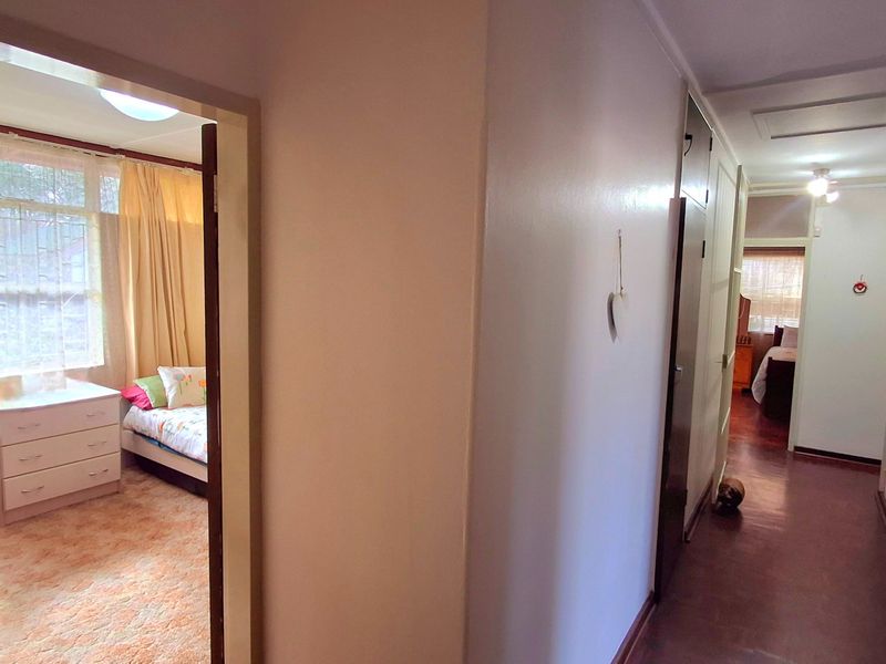 A functional hallway featuring built-in storage cupboards and access to adjacent bedrooms, finished with standard flooring and neutral wall tones.