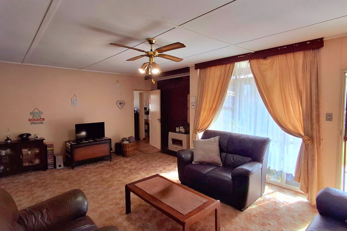 Spacious living room featuring a built-in fireplace, ceiling fan, and sliding glass door access to the exterior.