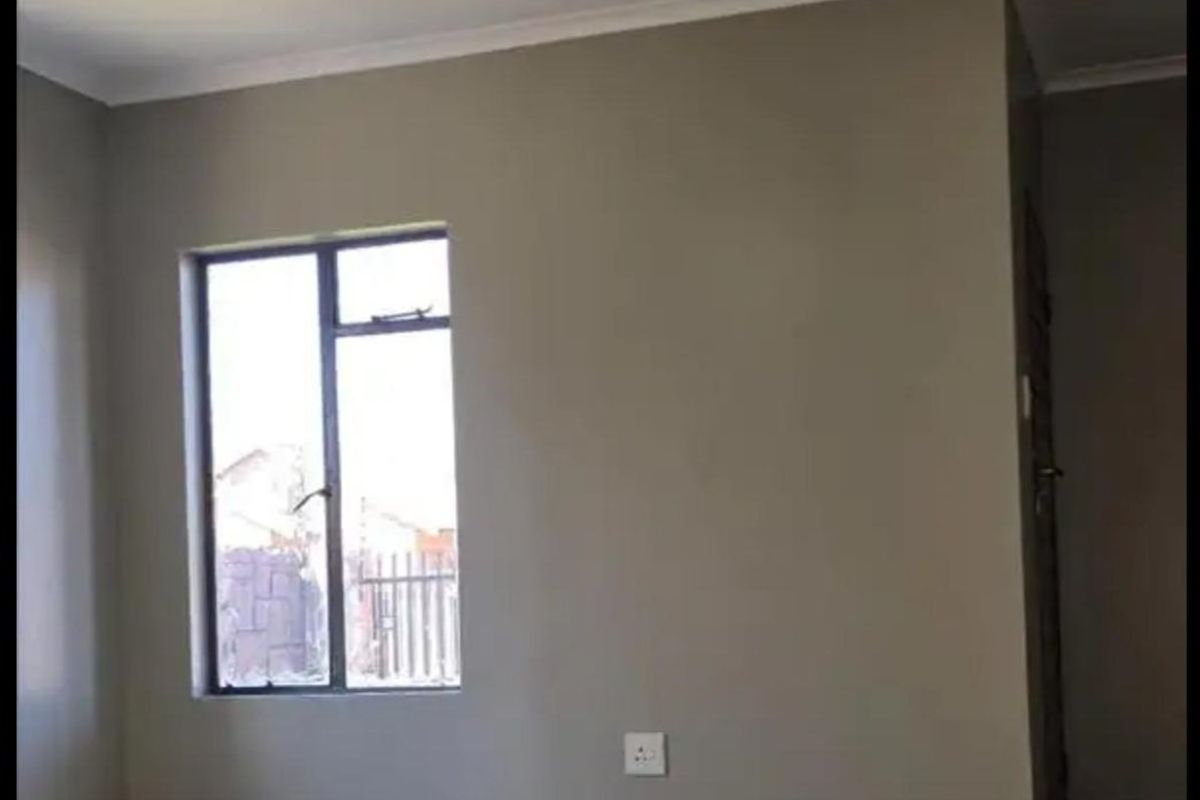 An empty living room featuring neutral wall paint, tiled flooring, and a ceiling fan, offering a clean and versatile space.