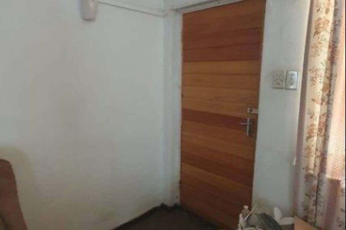 A small bedroom space featuring a timber door and coved ceiling, currently in need of cosmetic updates and refurbishment.