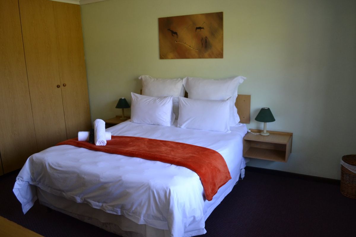 A functional bedroom featuring a built-in wardrobe and wall-mounted floating bedside tables, providing a clean and practical sleeping space.