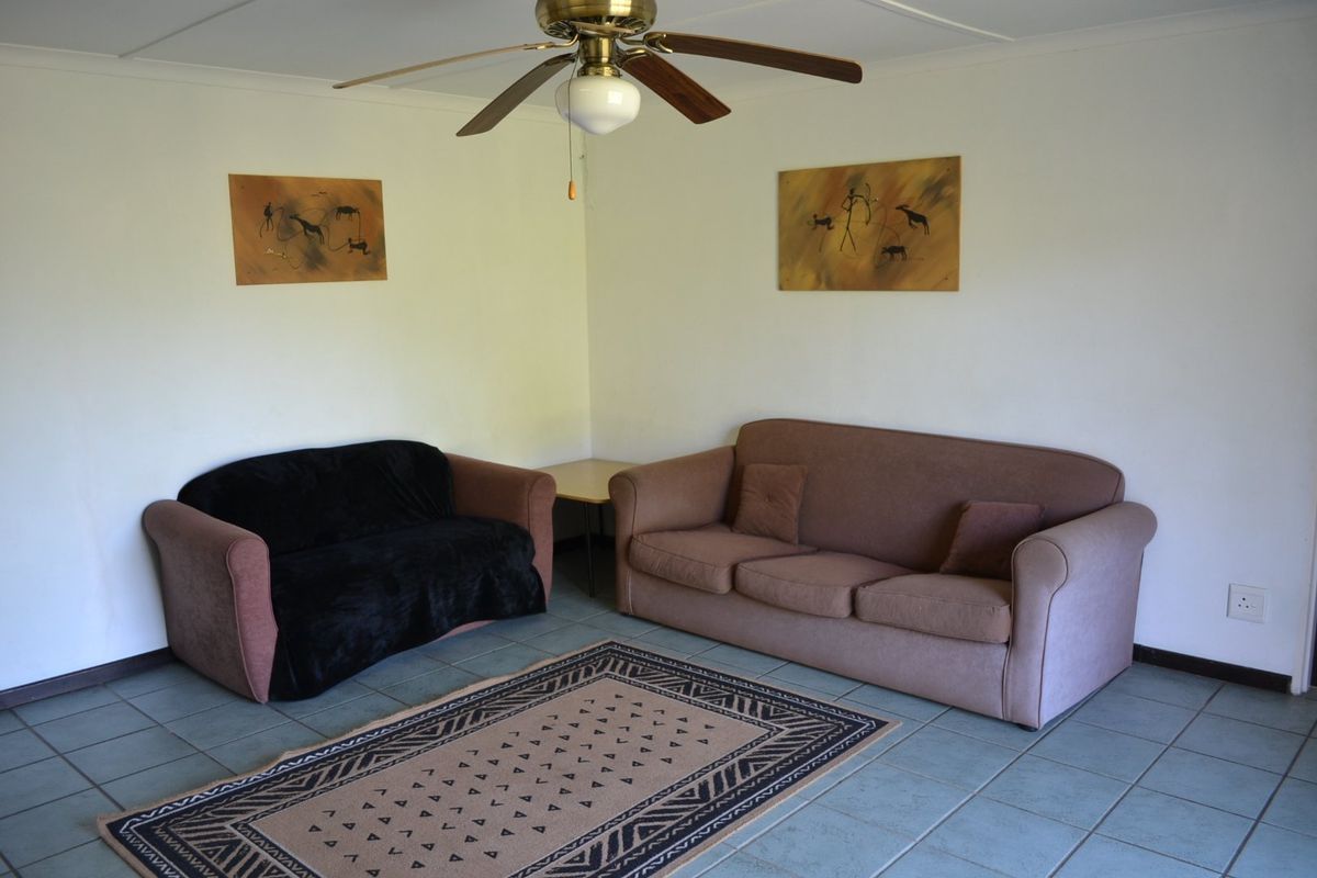 A simple living room area featuring tiled flooring and a central ceiling fan, providing a functional and neutral space.