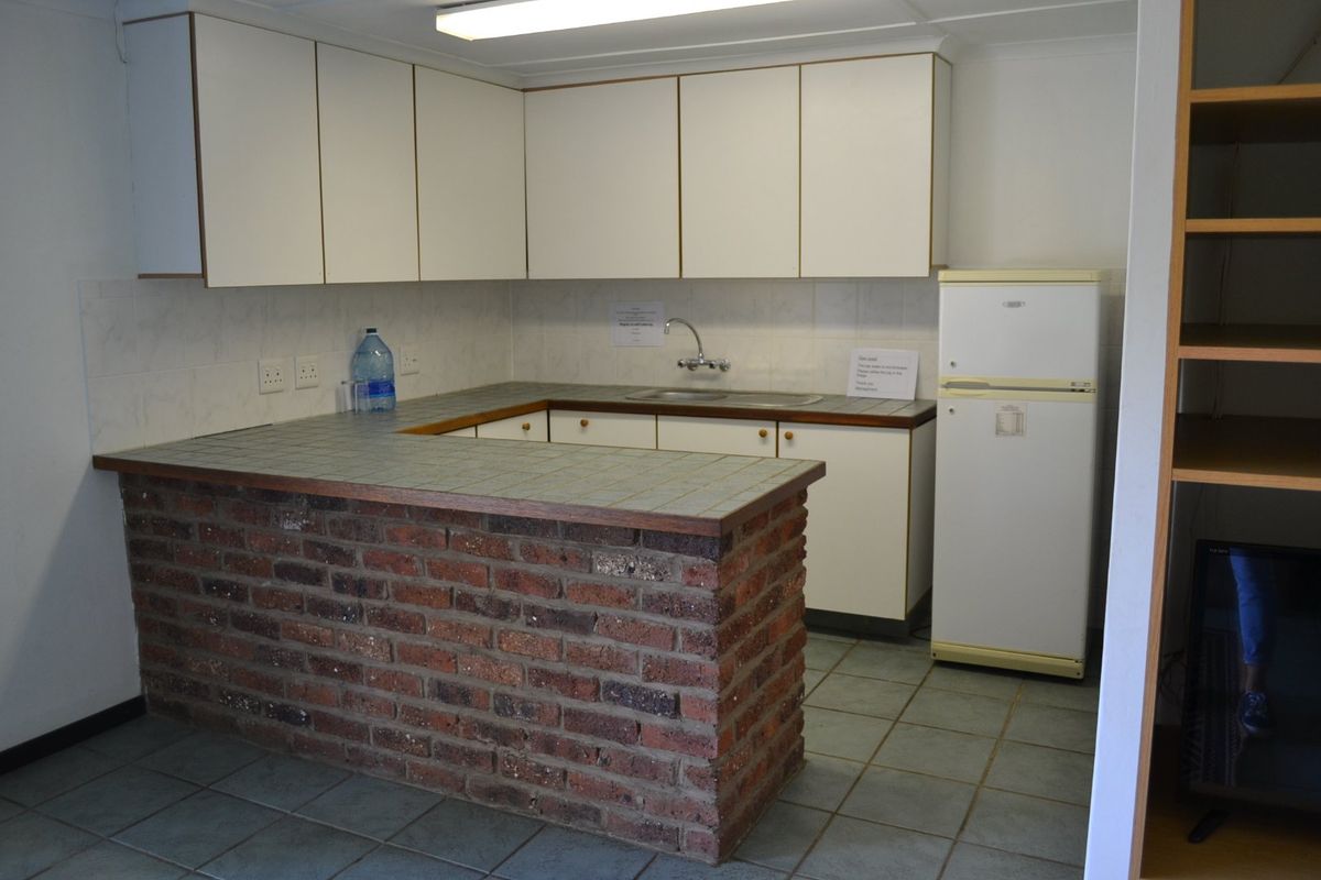A functional kitchen area featuring a brick breakfast bar, tiled countertops, built-in cabinetry, and tiled flooring.