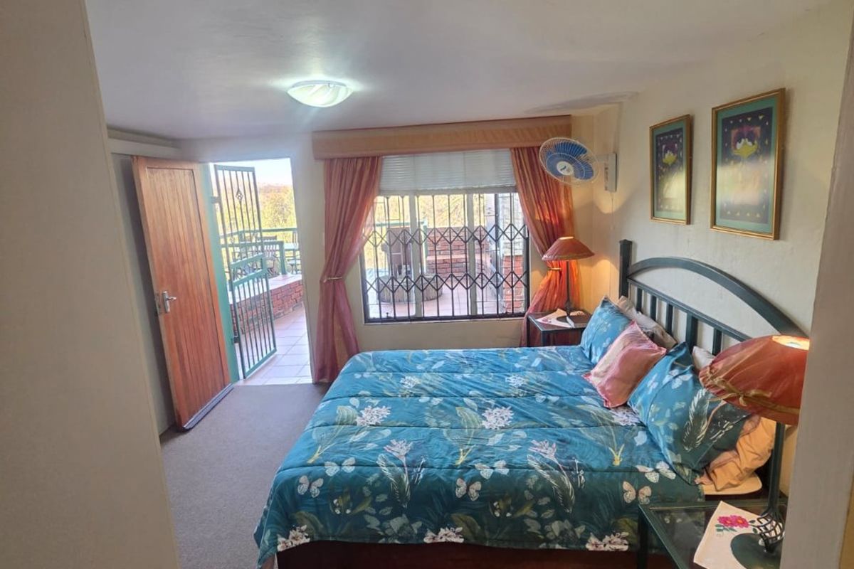 A bedroom featuring carpet flooring, security bars on the window, and direct access to an outdoor balcony area.