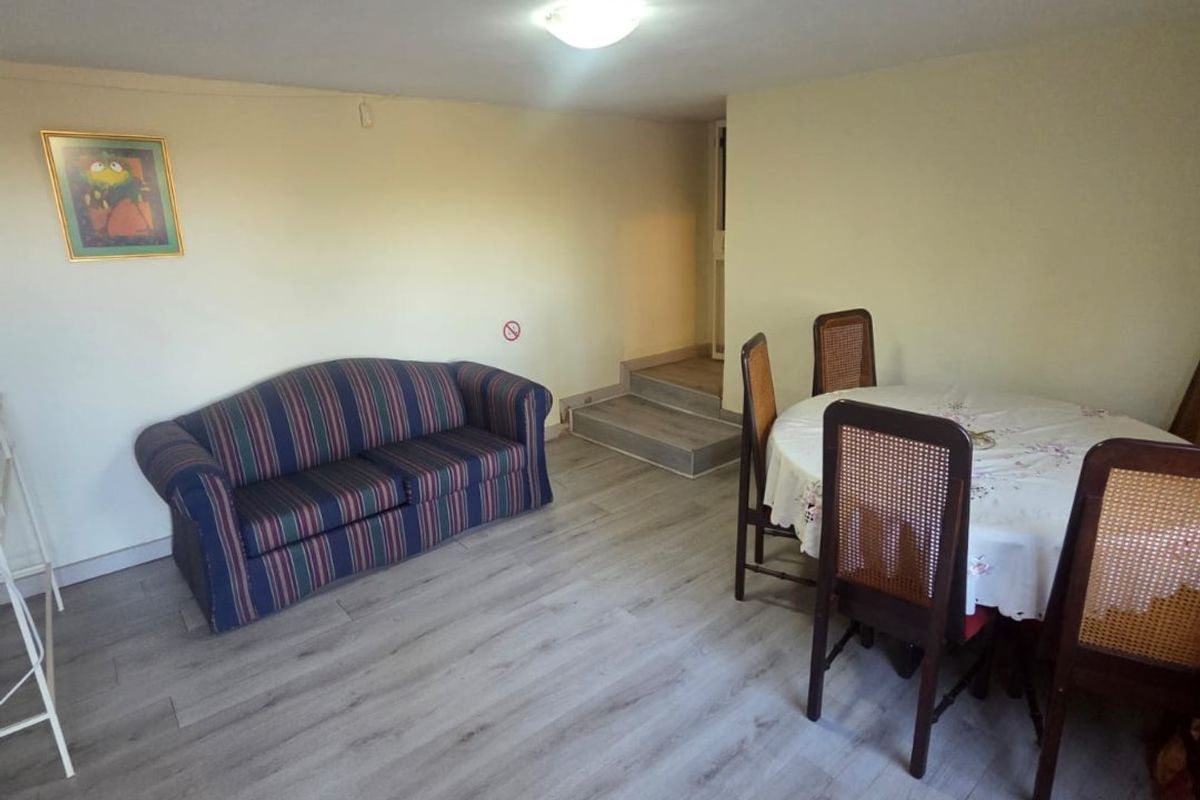A living and dining area featuring modern laminate flooring and a staircase leading to an upper level.
