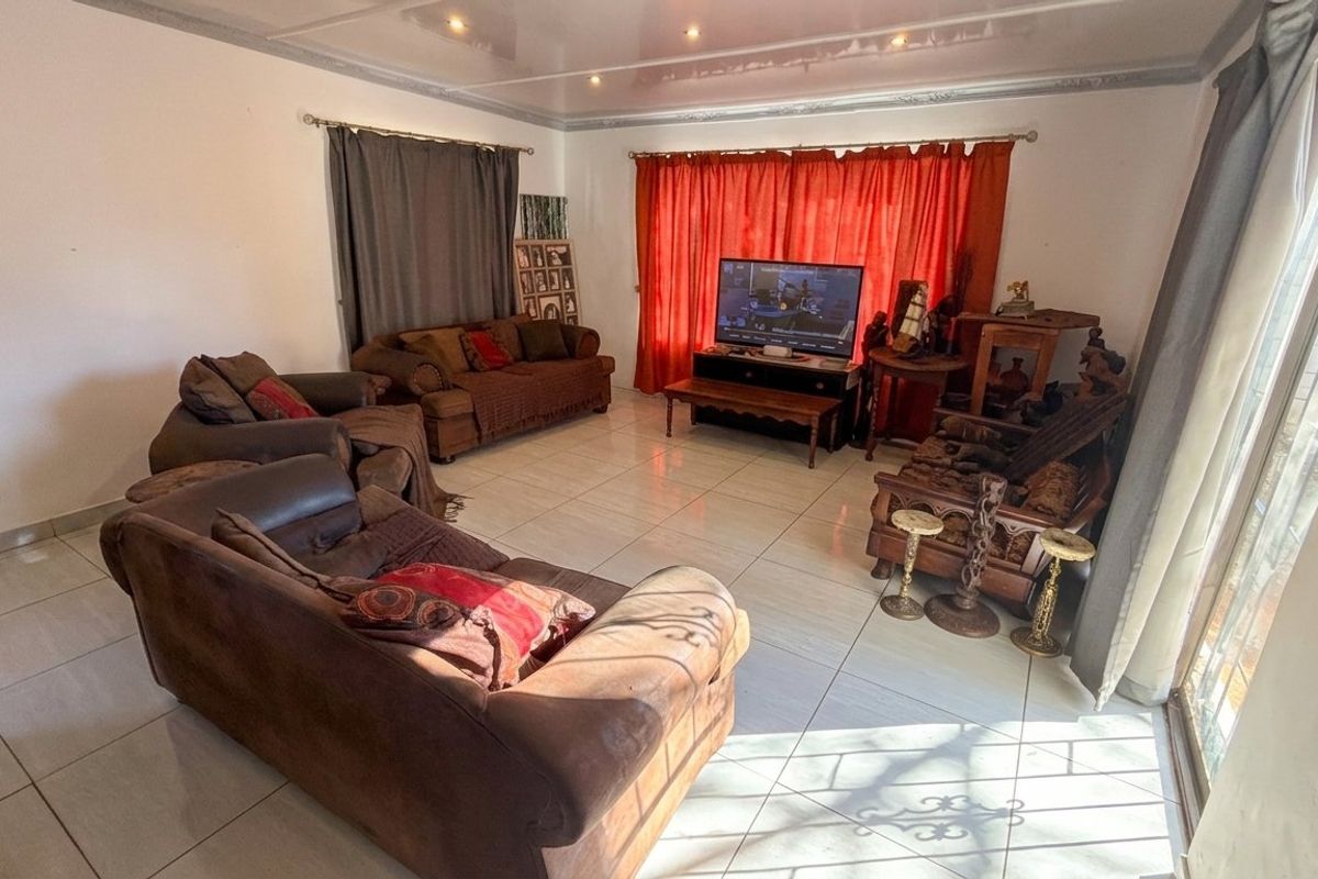 Spacious living room featuring large format floor tiles, recessed ceiling lighting, and a sliding glass door providing natural light.