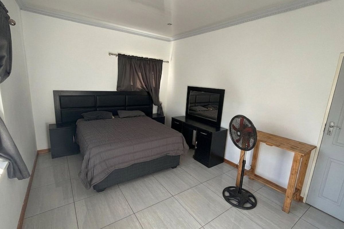 A bedroom featuring neutral tiled flooring, white walls, and coved ceiling detailing, providing a clean and functional space.