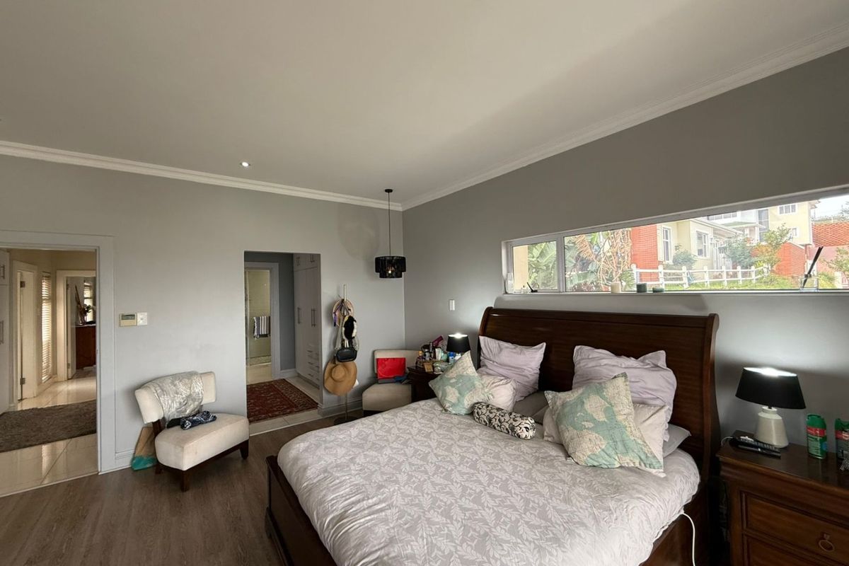Spacious bedroom featuring laminate flooring, neutral wall tones, built-in cupboards, and a horizontal clerestory window providing natural light.