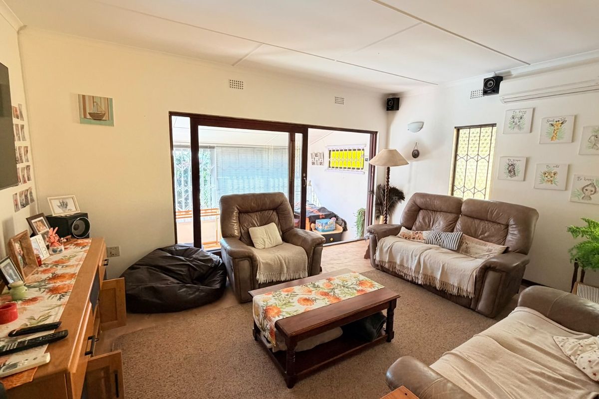 A comfortable living room featuring a sliding glass door leading to an outdoor area, wall-mounted air conditioning, and integrated speaker system.