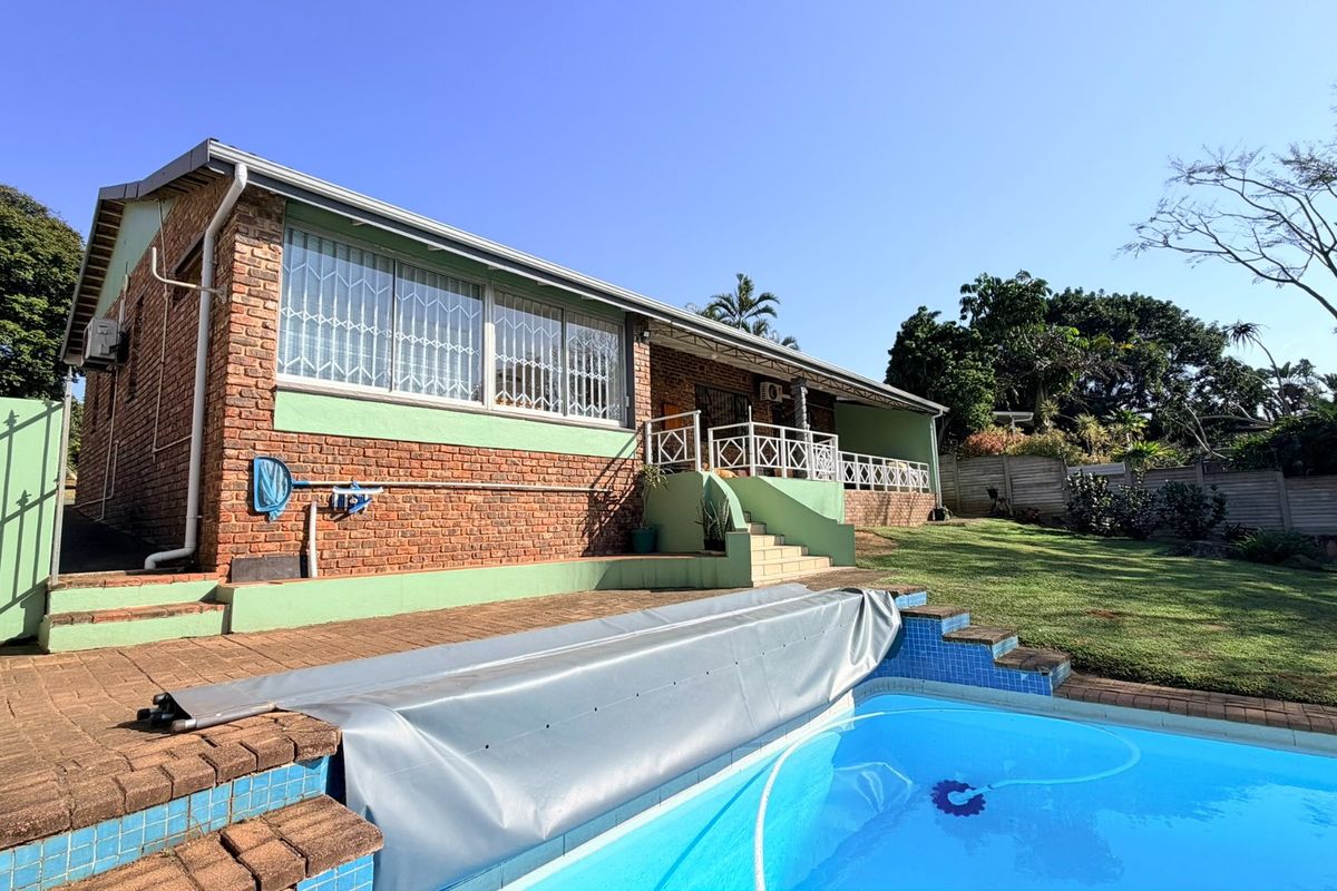 Rear view of the house featuring a swimming pool with a cover, a brick facade, and a covered patio area with security bars.