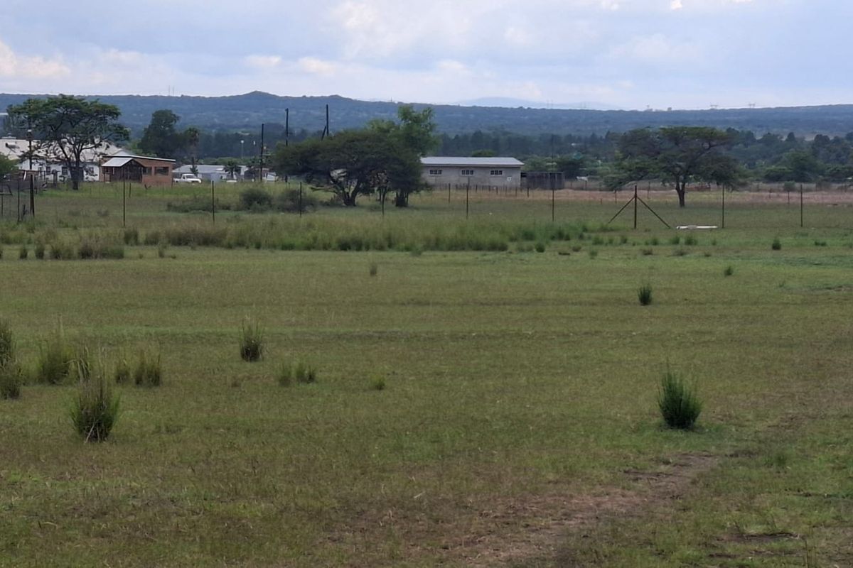Expansive view of the open farm landscape featuring natural pasture land and perimeter wire fencing under a cloudy sky.