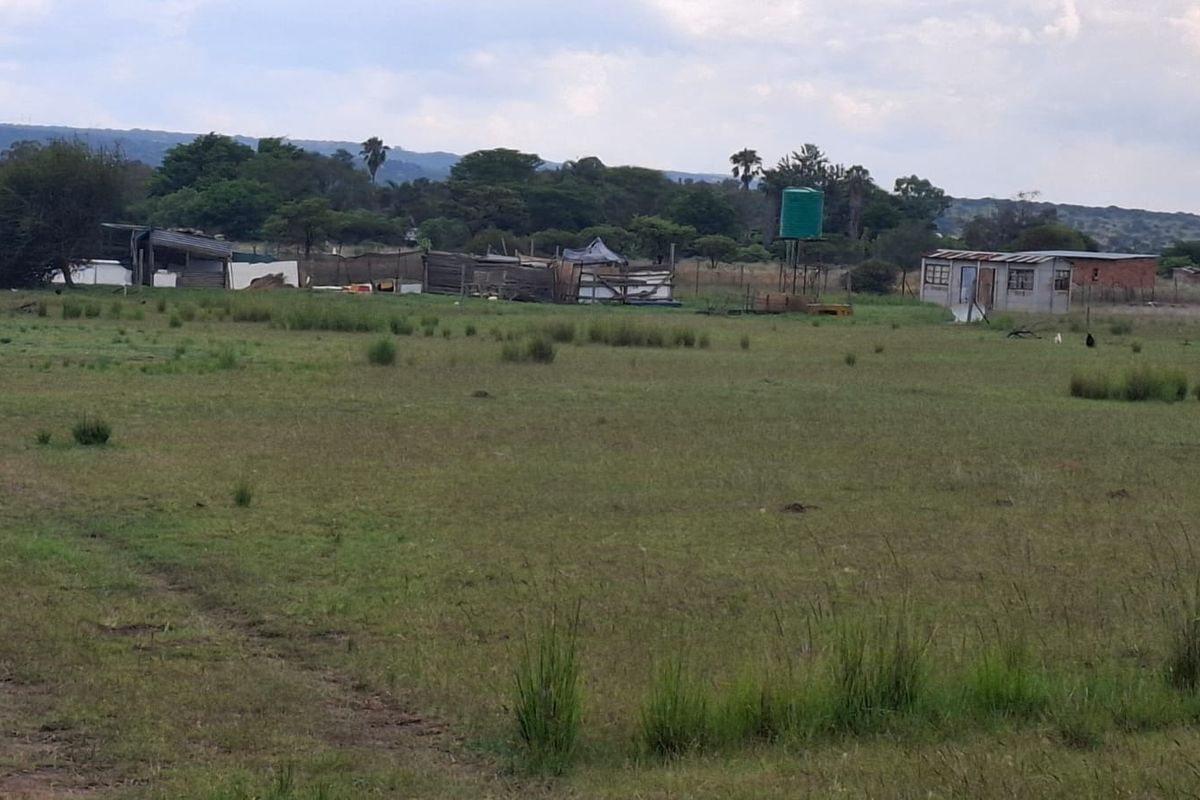 Expansive farm land featuring multiple outbuildings, perimeter fencing, and a water storage tank set against a rural landscape.