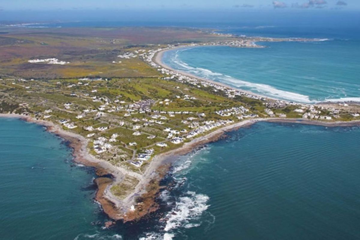 An expansive aerial view of the coastal residential area, showcasing the property's prime location along the shoreline and surrounding landscape.