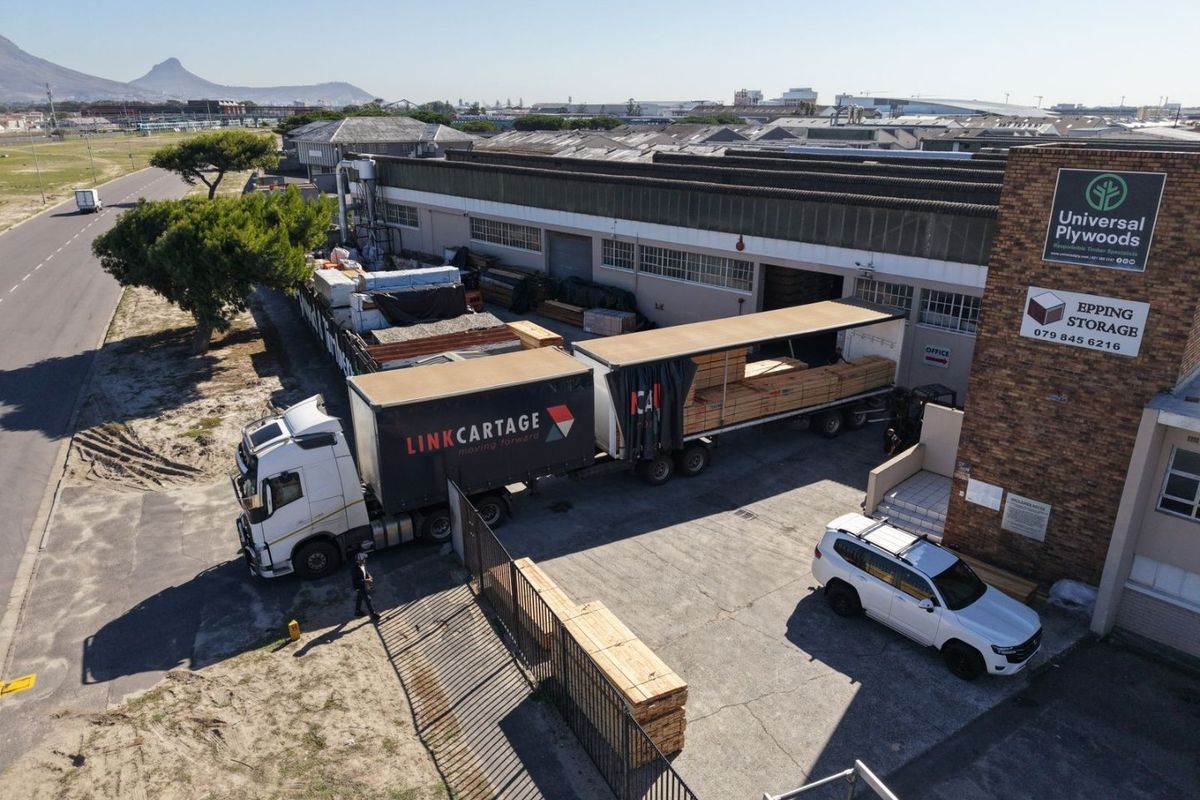 Aerial view of an industrial warehouse facility featuring a brick facade, concrete loading yard, and direct street access for logistics and storage operations.