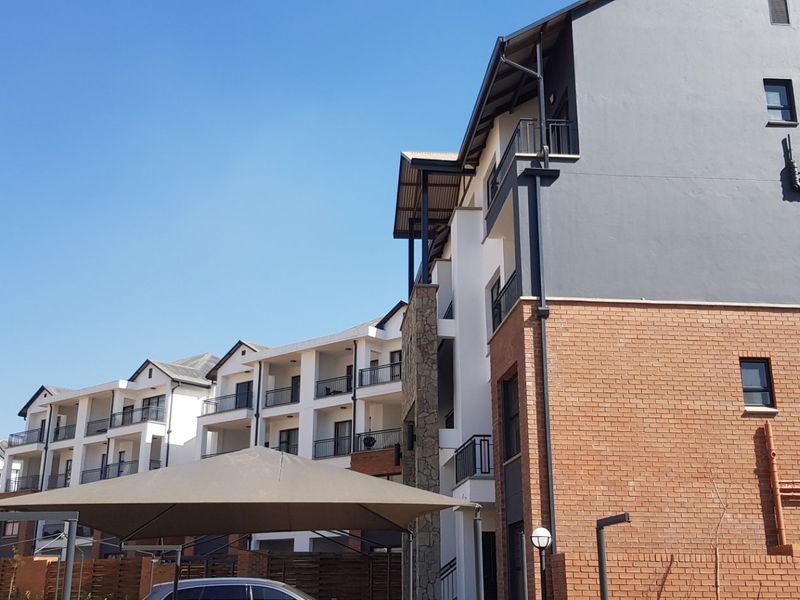 A view of the apartment complex exterior featuring brick and rendered facades, multiple balconies, and functional downpipe infrastructure.