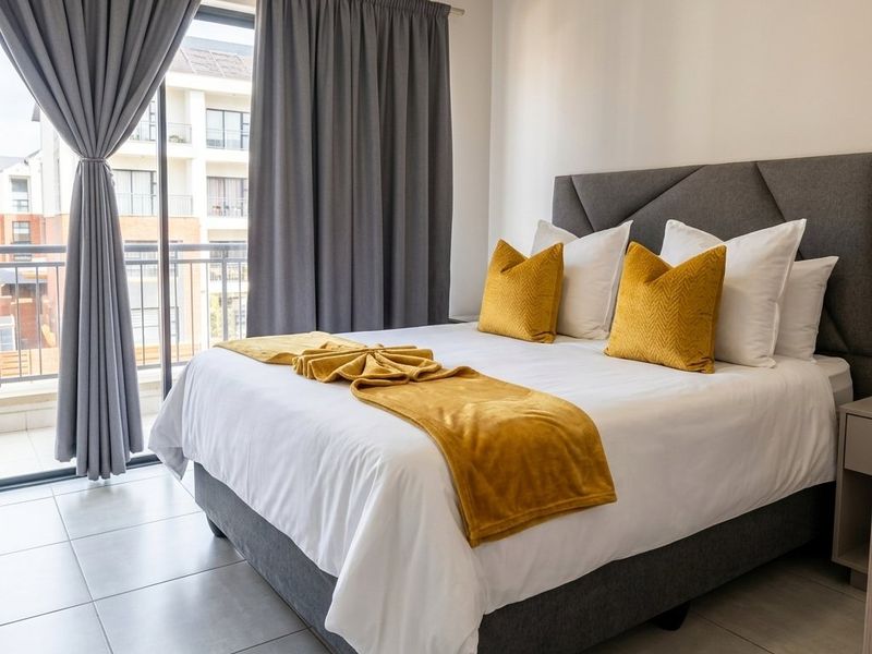 A well-maintained bedroom featuring neutral tiled flooring and a large sliding glass door providing direct access to a private balcony.