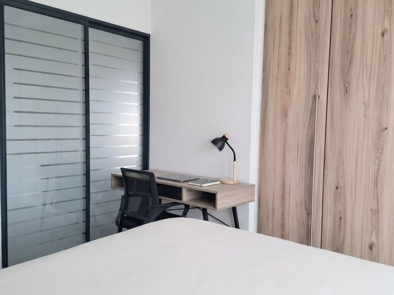 A well-maintained bedroom featuring modern wood-finish built-in wardrobes and a sleek sliding glass door, providing a clean and functional living space.