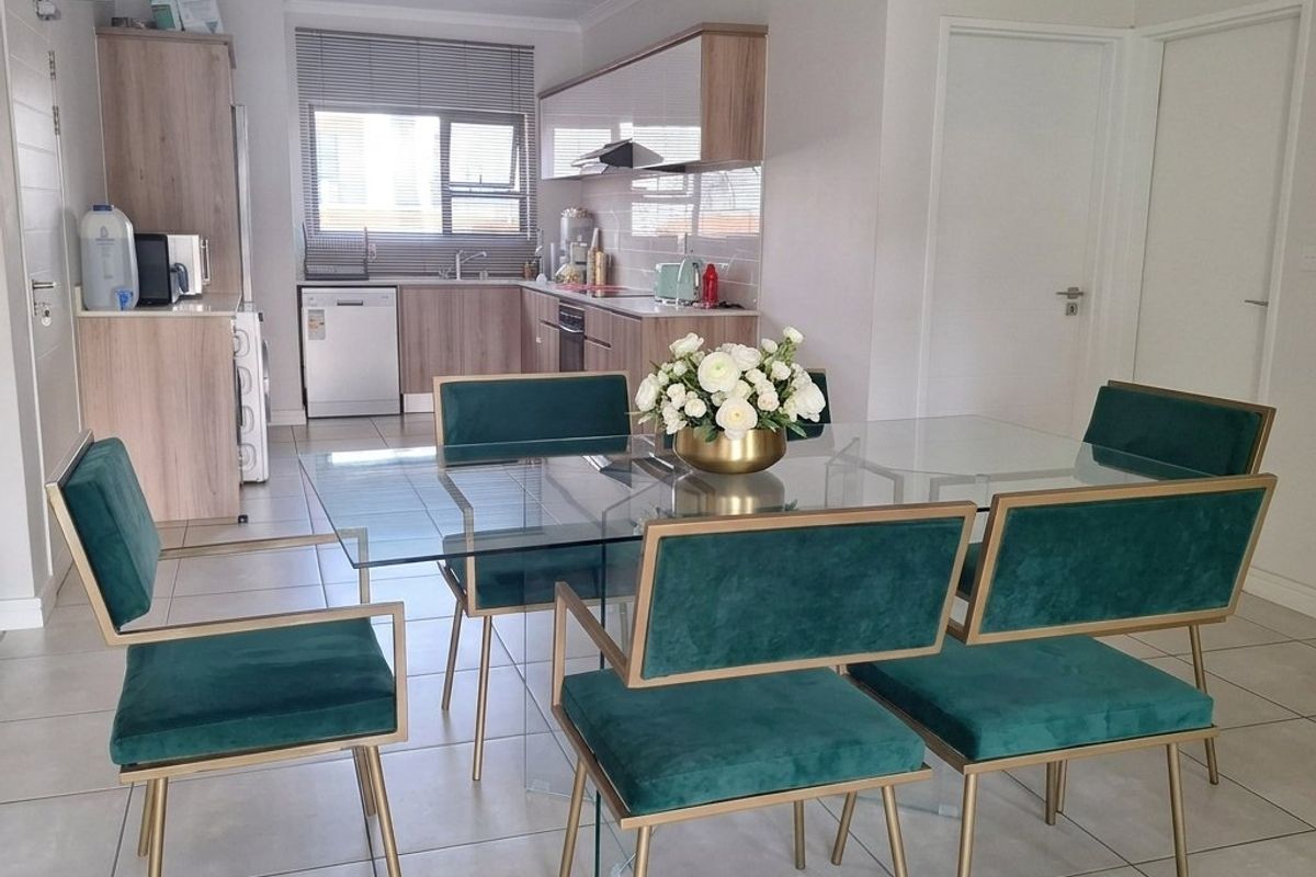An open-plan living and dining area featuring modern kitchen cabinetry, tiled flooring, and a functional layout with integrated kitchen fixtures.