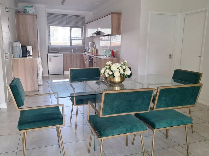 An open-plan living and dining area featuring modern kitchen cabinetry, tiled flooring, and a functional layout with integrated kitchen fixtures.