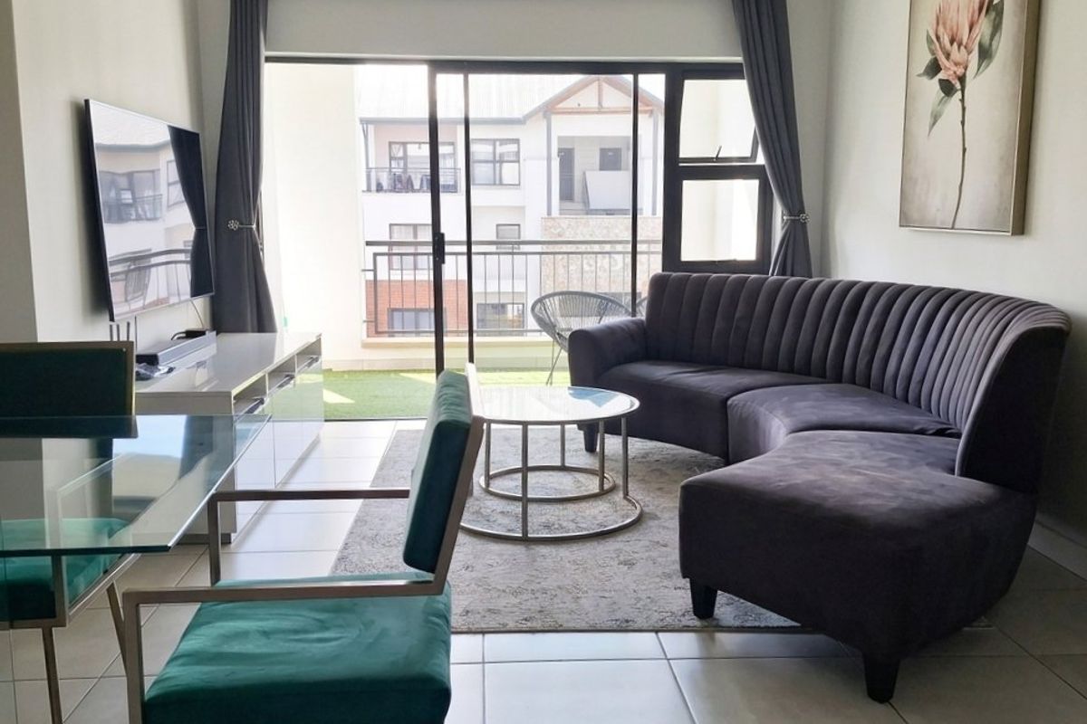 Open-plan living area featuring neutral tiled flooring and a large sliding glass door providing access to a private balcony.