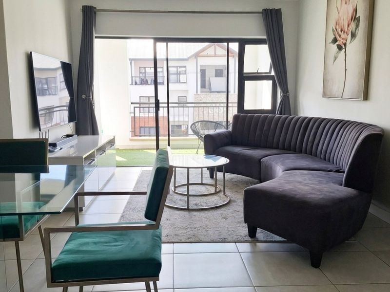 Open-plan living area featuring neutral tiled flooring and a large sliding glass door providing access to a private balcony.