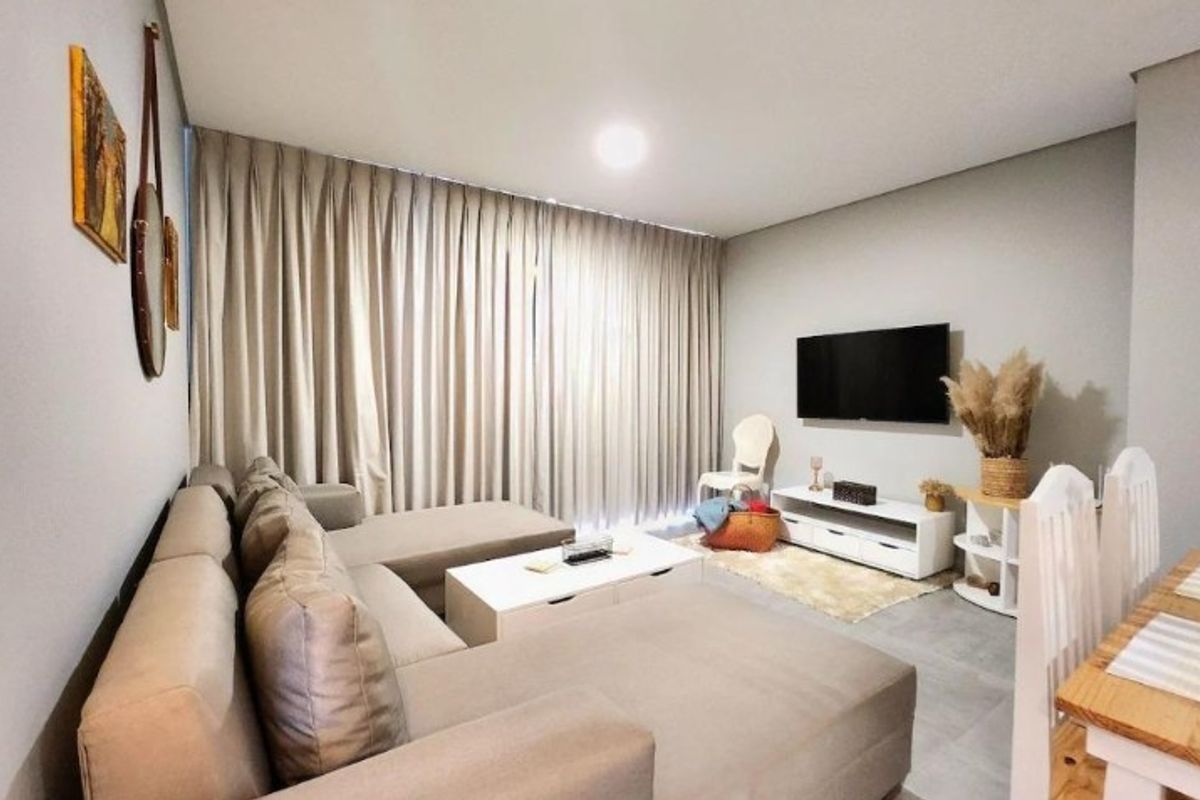 A well-maintained living room featuring neutral wall tones, tiled flooring, and recessed ceiling lighting, creating a bright and comfortable living space.