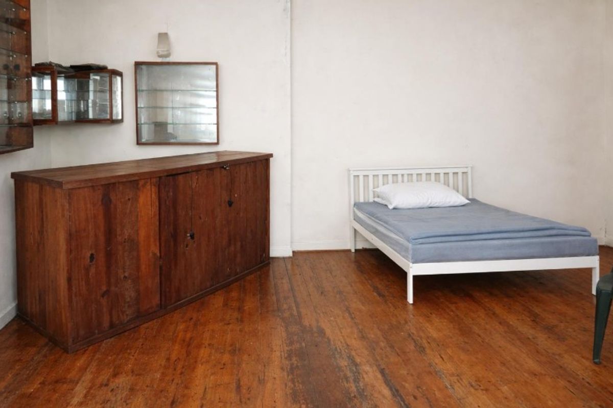 A bedroom featuring original hardwood flooring and wall-mounted storage units, offering a blank canvas for renovation and interior design updates.