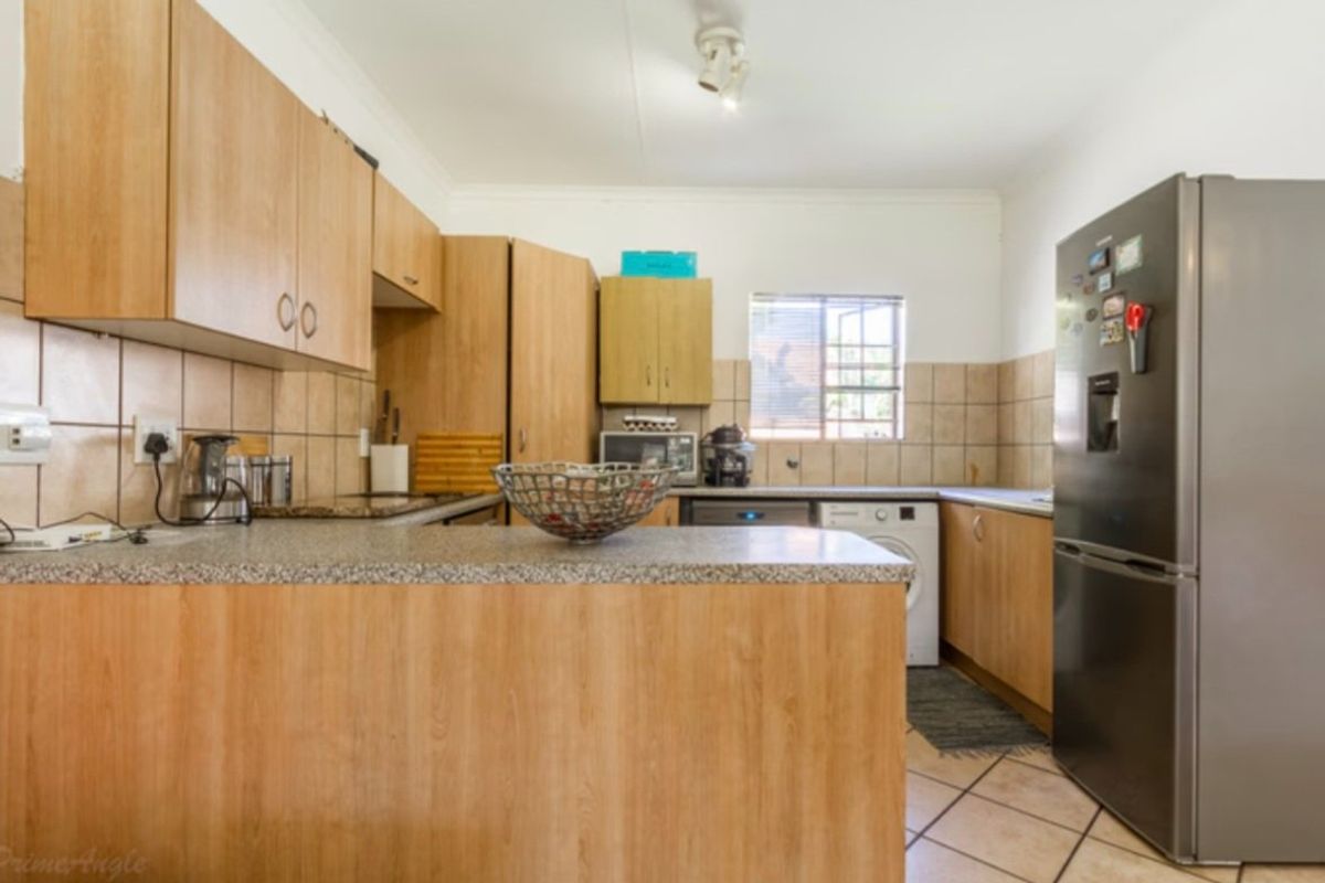 Functional kitchen featuring laminate cabinetry, granite countertops, tiled backsplash, and ceramic floor tiles, offering a practical layout for daily meal preparation.