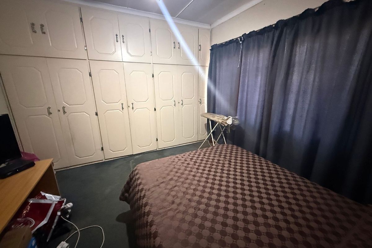 A bedroom featuring extensive floor-to-ceiling built-in cupboards and a ceiling fan, offering ample storage space.