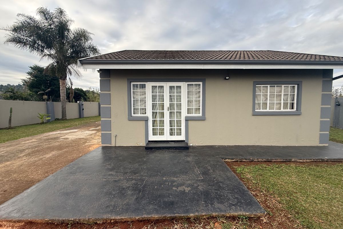 Rear view of the property featuring a concrete patio, french doors, and a tiled roof, set within a fenced garden area.