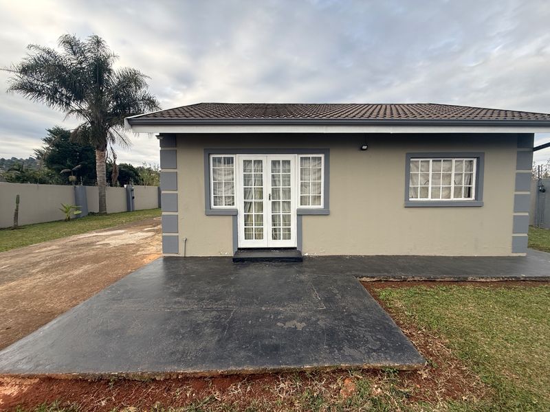 Rear view of the property featuring a concrete patio, french doors, and a tiled roof, set within a fenced garden area.