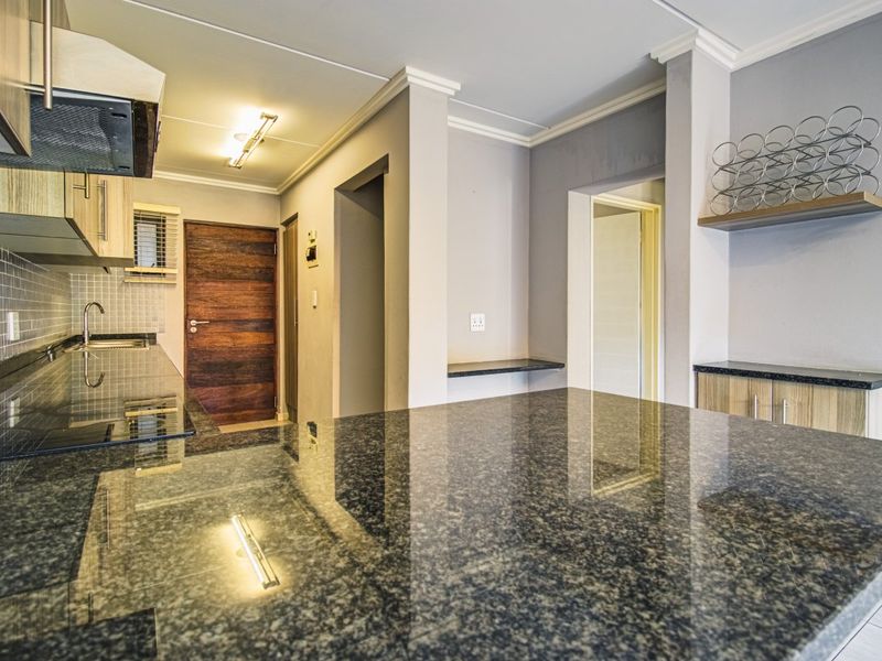 Modern kitchen featuring granite countertops, ample built-in cabinetry, a tiled backsplash, and an integrated extractor fan in a clean, neutral space.