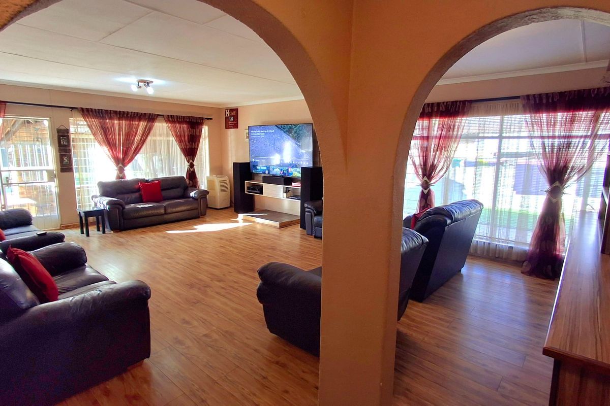 Spacious living area featuring laminate flooring and distinctive arched architectural details, providing a comfortable and open layout for family relaxation.