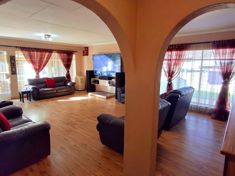 Spacious living area featuring laminate flooring and distinctive arched architectural details, providing a comfortable and open layout for family relaxation.