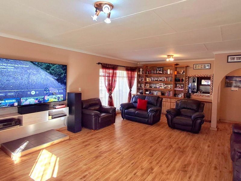 Spacious living room featuring laminate flooring, a built-in wooden shelving unit, and an arched entryway leading to adjacent areas.
