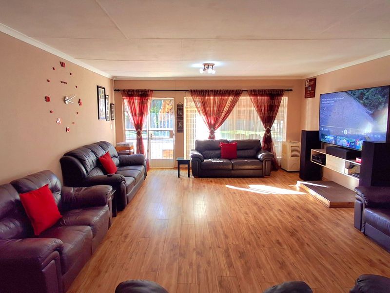 Spacious living room featuring laminate flooring, neutral wall tones, and a sliding glass door providing access to the outdoor area.