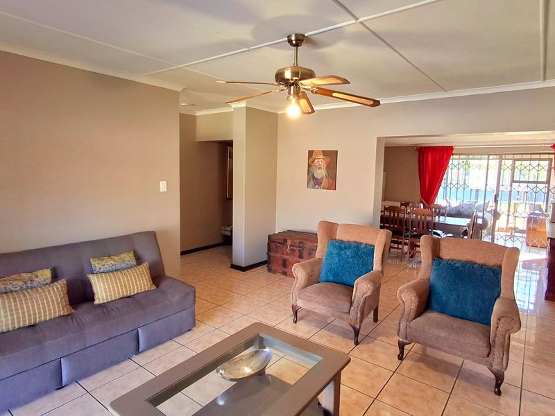 Open plan living and dining area featuring tiled flooring, a ceiling fan, and sliding glass doors leading to the exterior.