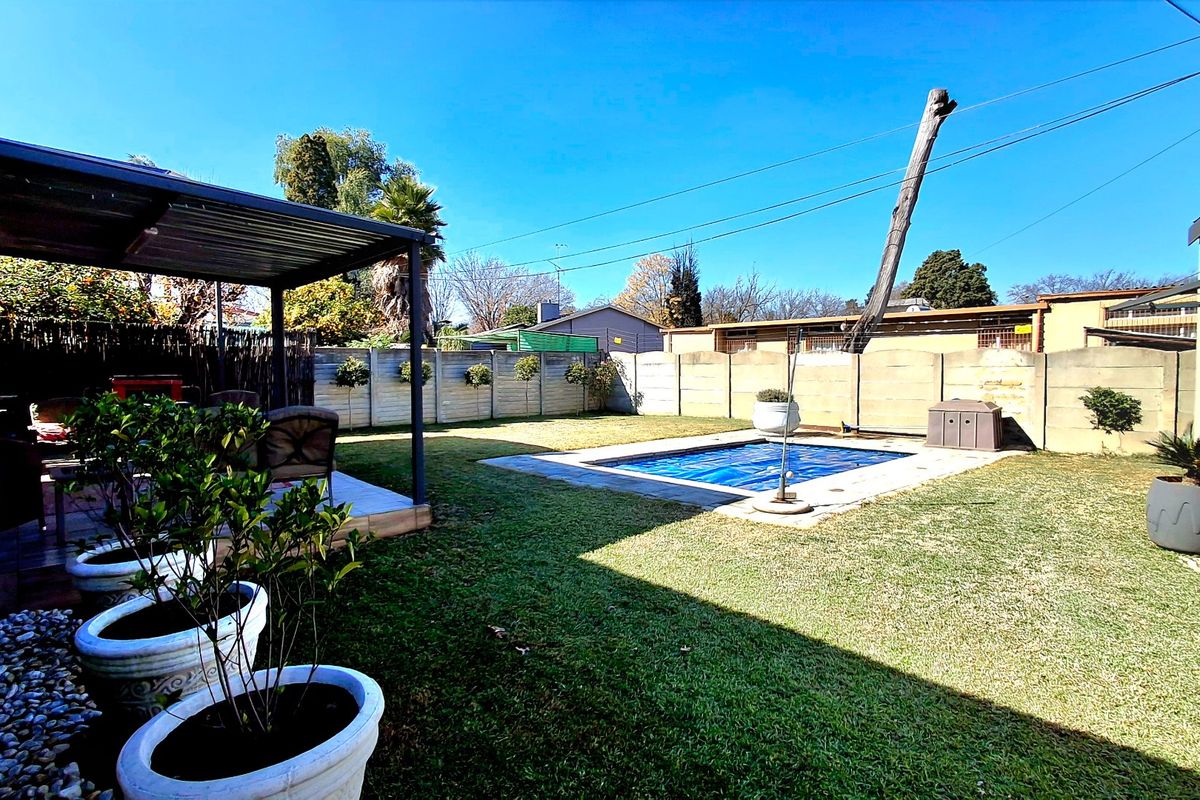 Rear garden area featuring a swimming pool with a cover, a covered patio space, and perimeter precast concrete walling.
