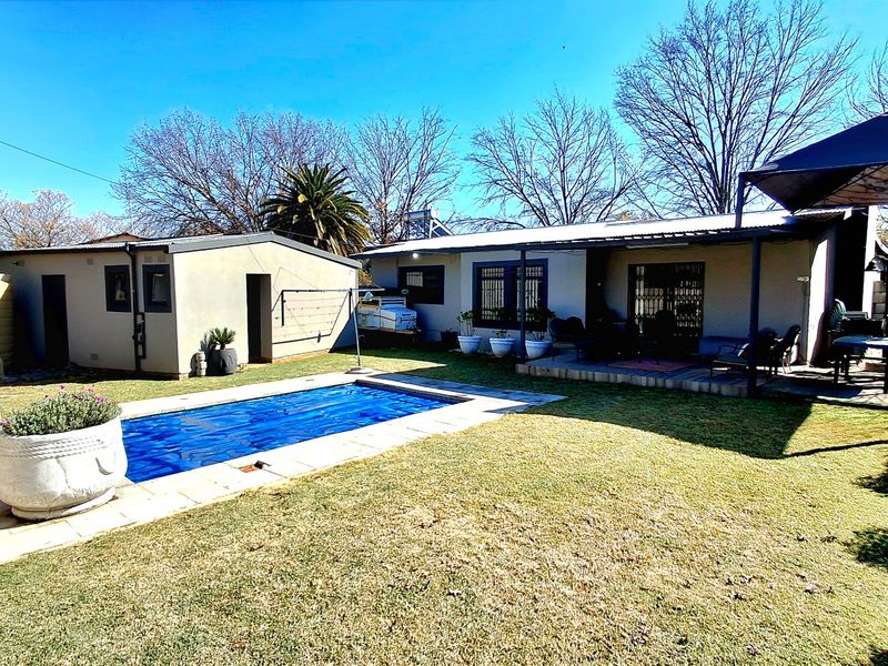 Rear garden featuring a swimming pool with cover, a covered patio area, and a separate outbuilding with a water tank.