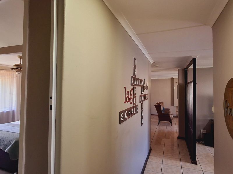 A functional hallway connecting living areas and bedrooms, featuring tiled flooring and a decorative partition screen.