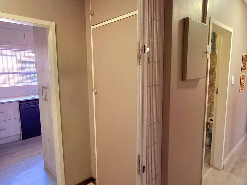 A functional hallway providing access to the kitchen and bathroom areas, featuring laminate flooring and built-in storage cupboards.