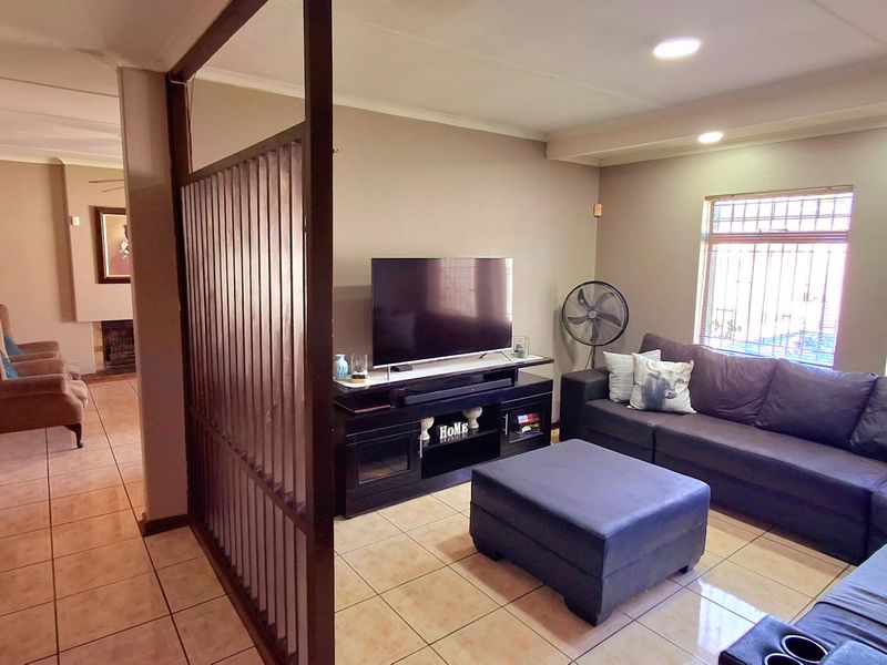 A living room featuring tiled flooring, recessed ceiling lighting, and a decorative room divider, with security bars installed on the windows.