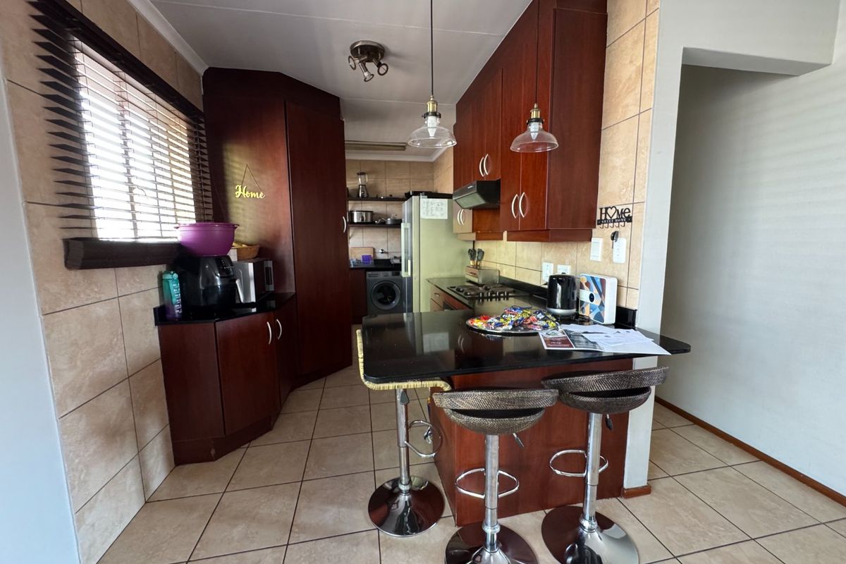 A functional kitchen featuring dark wood cabinetry, granite countertops, a gas hob, and tiled finishes, offering a practical layout for daily cooking.