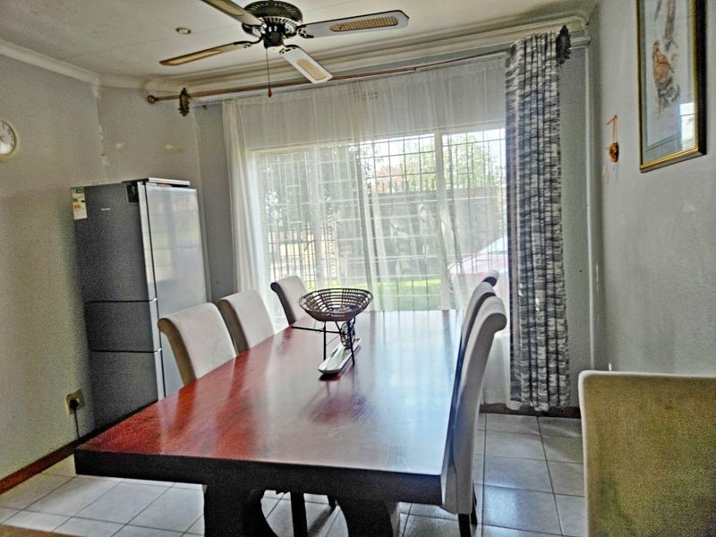 Dining area featuring tiled flooring, a ceiling fan, and a sliding glass door with security bars, providing access to the exterior.