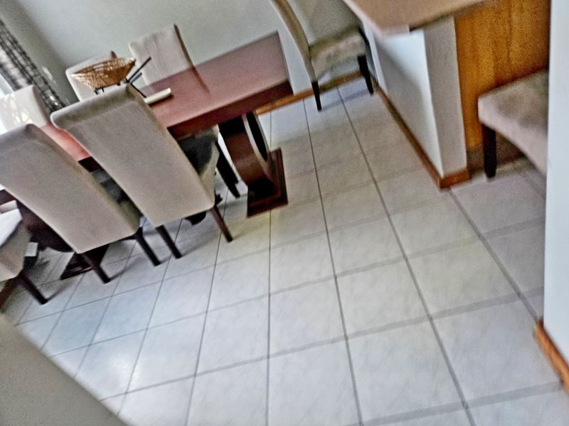 A dining area featuring tiled flooring and a breakfast bar, providing an open-plan layout suitable for casual meals and entertaining.