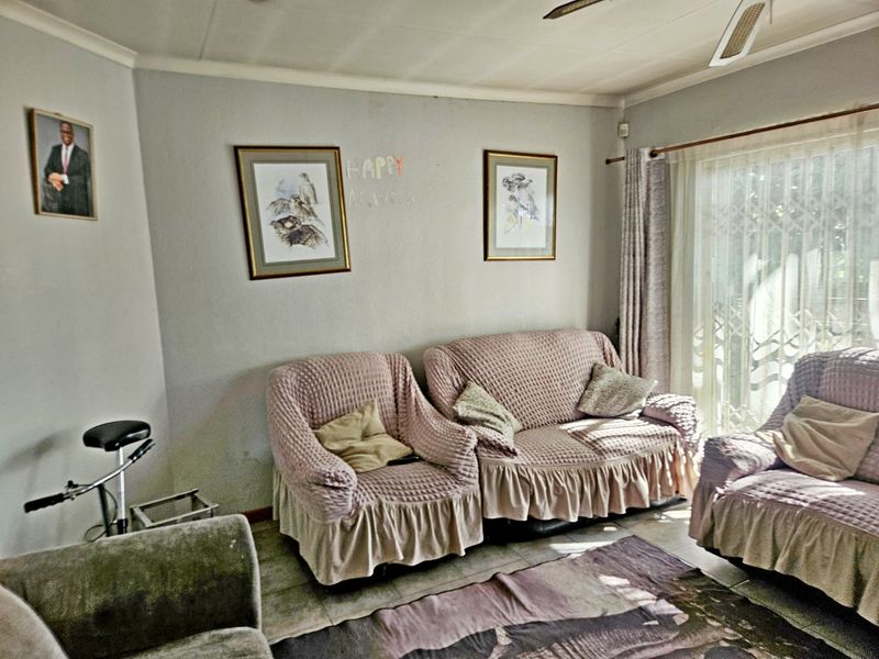 A living room featuring tiled flooring, a ceiling fan, and a sliding glass door with security gate access to the exterior.